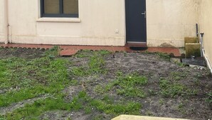 Ein kleines, eingeschossiges Gebäude mit Flachdach, schwarzer Tür und Fenster.