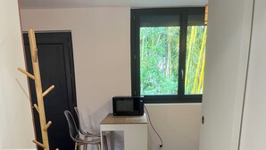 Eine kompakte Küche mit einer Mikrowelle auf einer kleinen Kochinsel, einem Holzanziehkleiderständer und einem Fenster mit Blick ins Grüne.