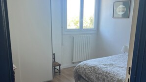 Makuuhuone, jossa on sänky, ikkuna, patteri ja tuoli.