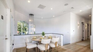 Un comedor con una mesa redonda, seis sillas y una araña.