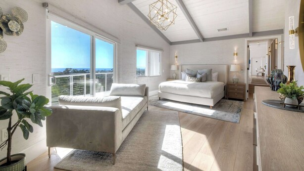 Un dormitorio amplio con una cama grande, una zona de estar con sofá y vistas al exterior.