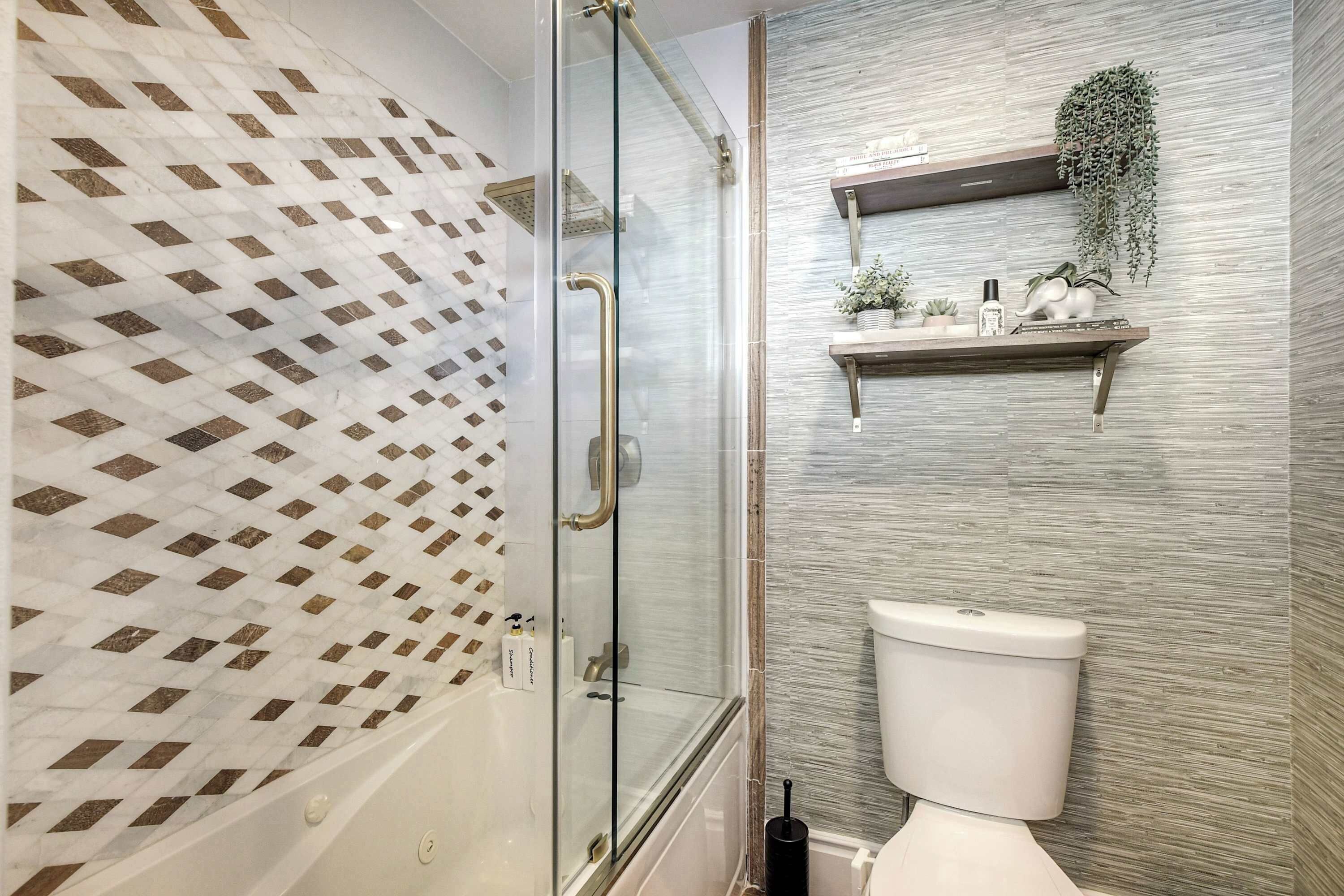 Ein Badezimmer mit einer gläsernen Duschkabine, einer Toilette und einem Regal mit Pflanzen und Pflegeprodukten.