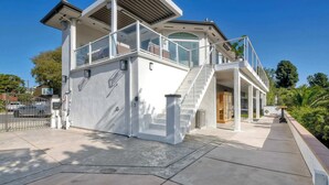 Una casa moderna de dos pisos con balcón, escaleras y un espacio exterior cubierto.