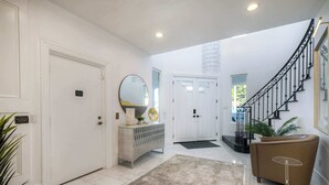 Un interior moderno con una escalera, una puerta blanca, una consola y una planta en maceta.