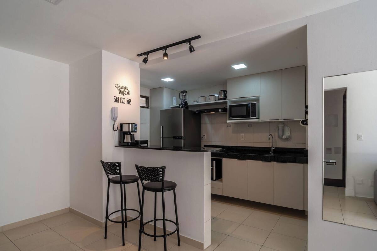 Cozinha moderna com ilha central, banquetas e máquina de café.