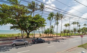 Eine Küstenstraße mit Palmen und einem Strand im Hintergrund.