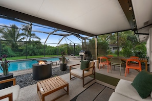 A covered outdoor seating area with a pool, a fire pit, and a grill. - Sun-Kissed Modern Oasis with Private Heated Pool (Fort Myers)