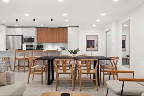 A modern kitchen with white cabinets, a black countertop, and stainless steel appliances. - Sun-Kissed Modern Oasis with Private Heated Pool (Fort Myers)