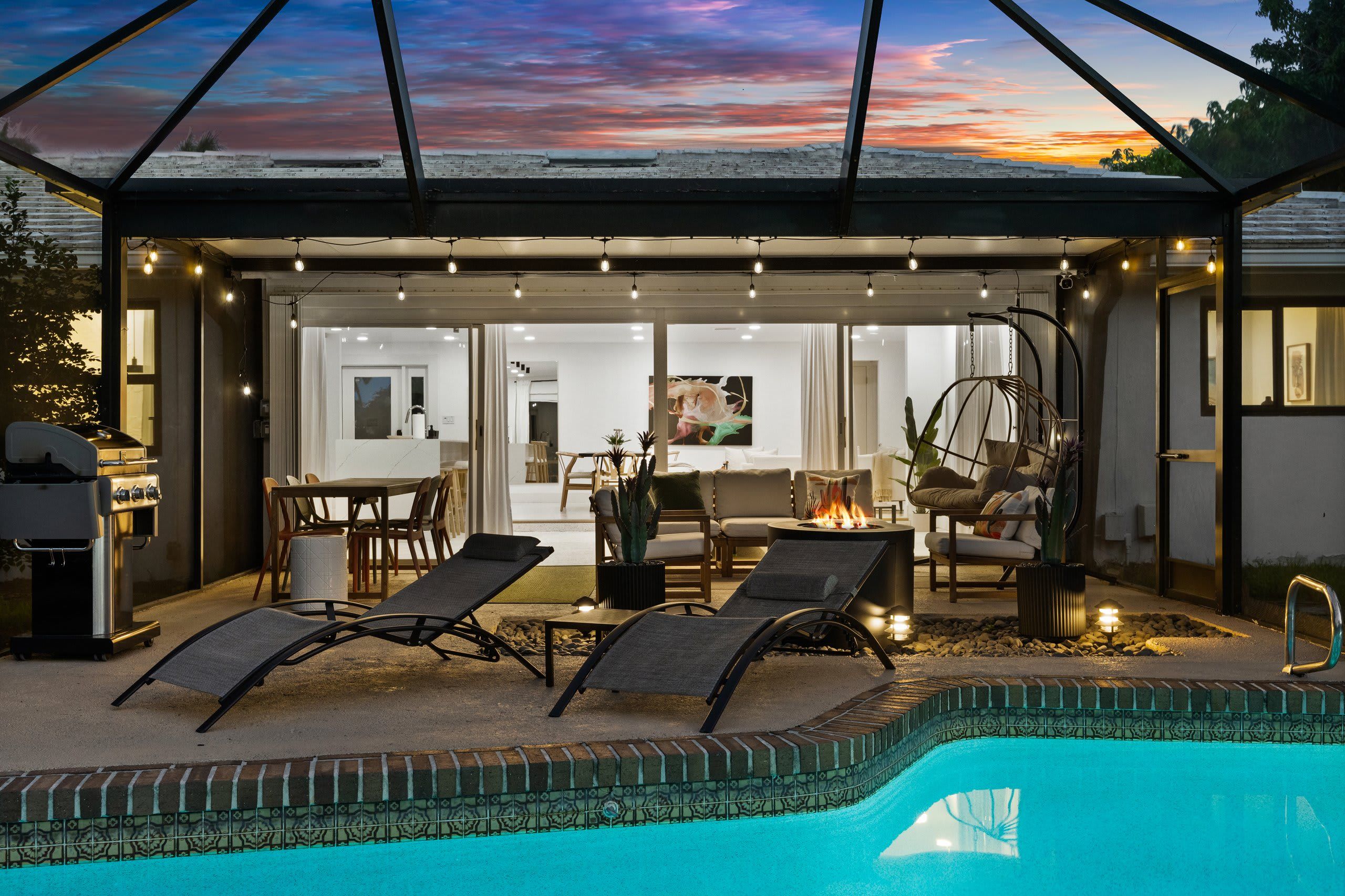 A poolside area with lounge chairs, a barbecue grill, and a fire pit.