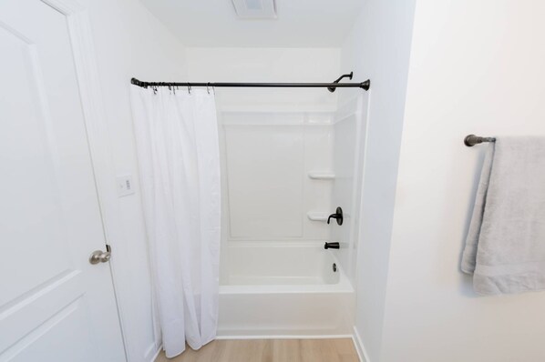 Un baño con ducha, inodoro y toallero.