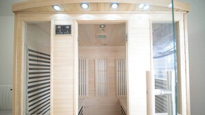Eine Sauna mit Holzvertäfelung, Bedienfeld und Glastür.