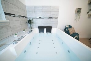 A modern bathroom with a large bathtub, a small sink, and a potted plant. - Aman private Jacuzzi, billiards and relaxation room (Mulhouse)