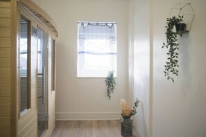 A hallway with a window, a door, and a plant on a wall. - Aman private Jacuzzi, billiards and relaxation room (Mulhouse)