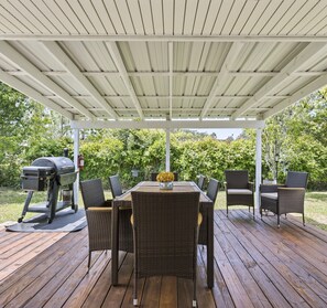 An outdoor patio with a covered seating area, a grill, and wicker furniture.