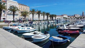 A marina with various boats docked, surrounded by buildings and palm trees. - A2 comfortable apartment with terrace and garden, 4 min walk to Znjan beach (Split)