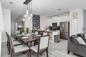 A modern kitchen with a central island, stainless steel appliances, and a chalkboard menu.