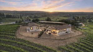 Ein Weingut mit einem großen Haus, Sitzgelegenheiten im Freien und einem überdachten Bereich.