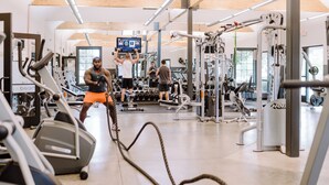 Ein Fitnessstudio mit Laufbändern, Kraftgeräten und einer Seilzugstation.