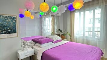 A modern bedroom with a large bed, a nightstand, a potted plant, and a window with curtains.