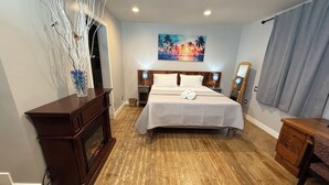 A bedroom with a large bed, wooden flooring, a nightstand, a dresser, a mirror, and a painting on the wall. - Charming Valley Home, Close to Top LA Attractions; Lovely 3-bedroom house (Los Angeles)