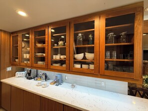 Cocina con armarios de madera, encimera de mármol y diversos electrodomésticos.