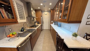 A modern kitchen with wooden cabinets, stainless steel appliances, and a marble countertop. - Charming Valley Home, Close to Top LA Attractions; Lovely 3-bedroom house (Los Angeles)