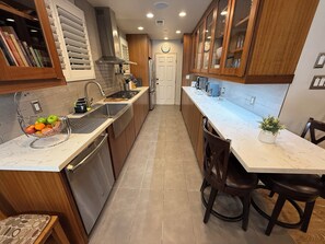 A modern kitchen with wooden cabinets, stainless steel appliances, and a marble countertop. - Charming Valley Home, Close to Top LA Attractions; Lovely 3-bedroom house (Los Angeles)