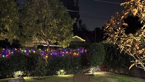 An outdoor patio area with a fire pit table surrounded by chairs, a brick pathway, and a grassy lawn. - Charming Valley Home, Close to Top LA Attractions; Lovely 3-bedroom house (Los Angeles)