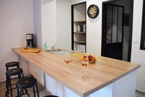 Eine moderne Küche mit Holzarbeitsplatte, einer Kaffeemaschine, einem Spülbecken und zwei Barhocker.