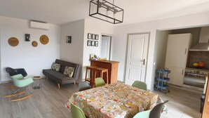 Uma sala de estar moderna com sofá, cadeiras, mesa de jantar e cozinha com armários e fogão.