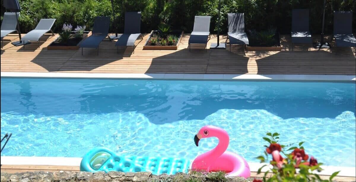 En swimmingpool med liggestole og en flamingo-svømmebøje.