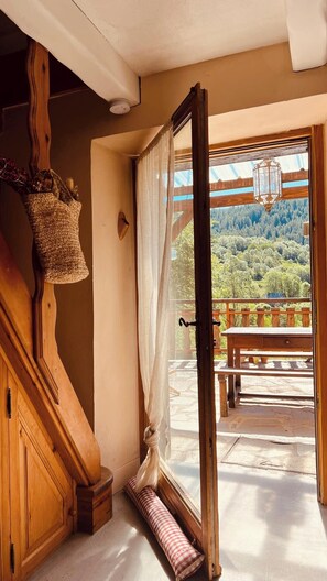 A wooden staircase leading to a balcony with a view of a forested landscape.