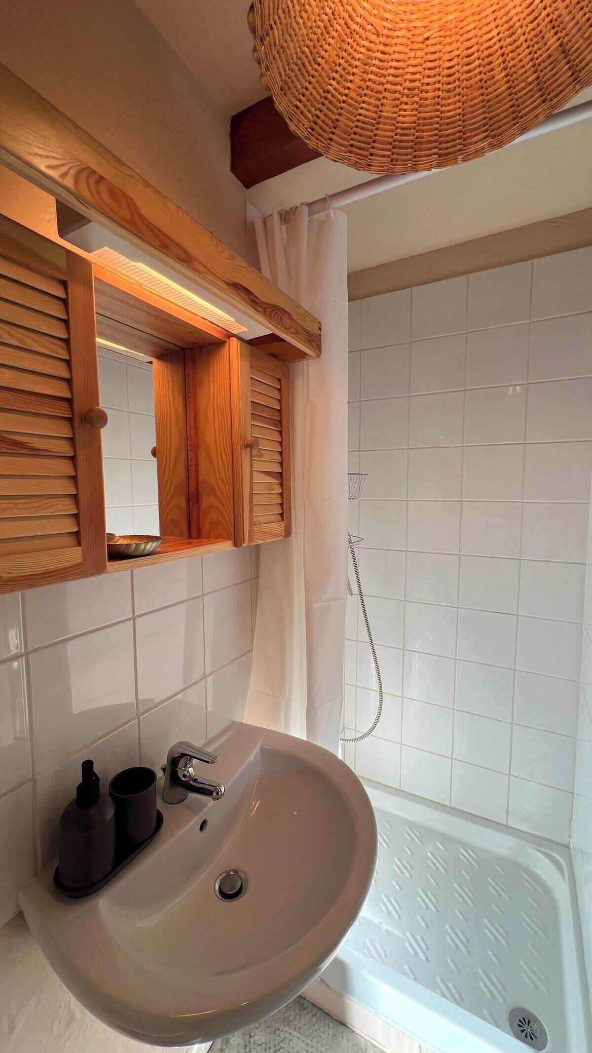 Une salle de bain avec un meuble-lavabo en bois, un évier, un miroir et un espace douche.