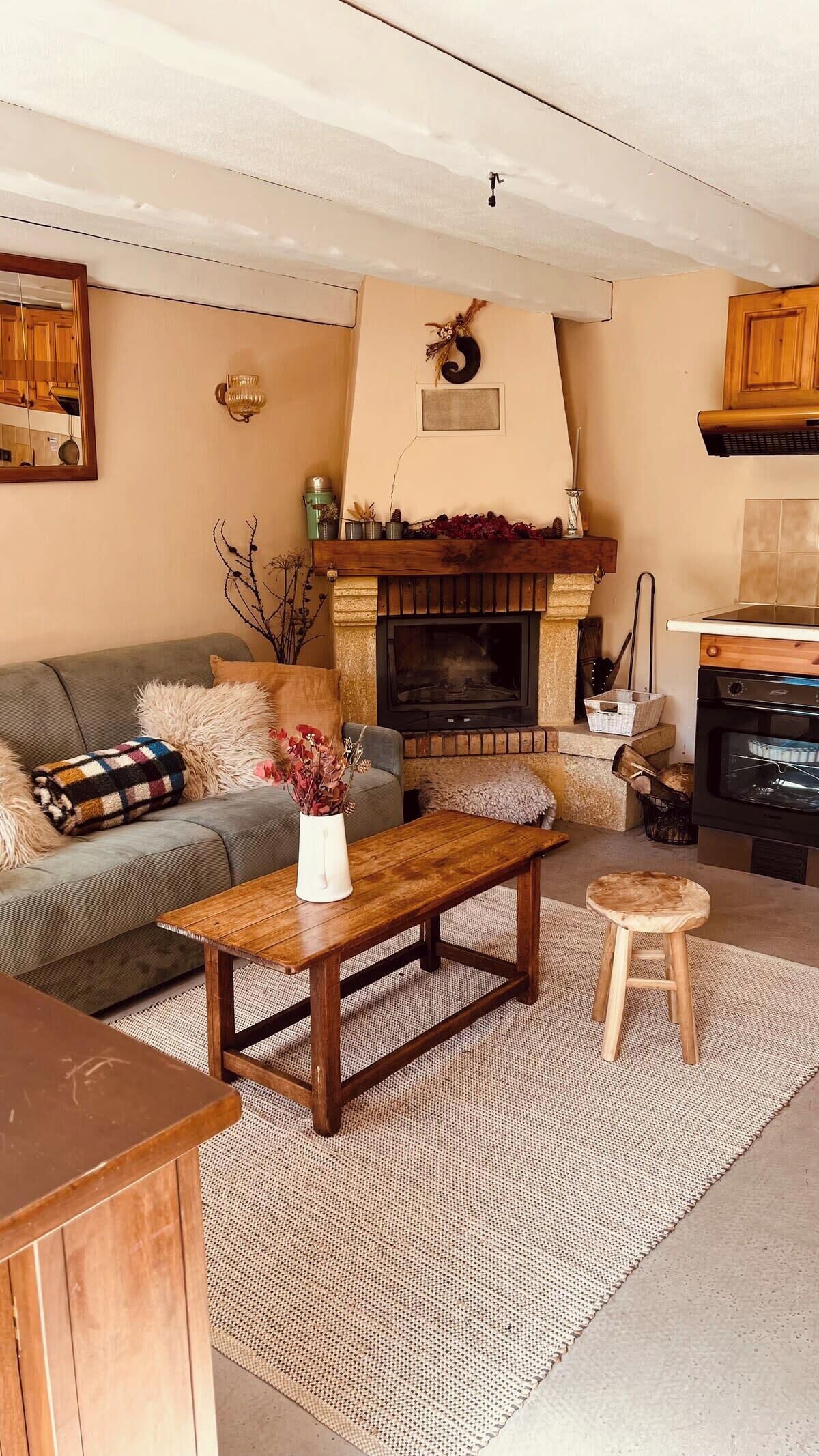 A cozy living room with a fireplace, a sofa, a coffee table, and a small stool.