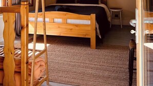 A bedroom with a wooden bed, a small table, a window with curtains, and a wooden ladder. - Grange pour 6 personnes avec studio indépendant (Beuil)
