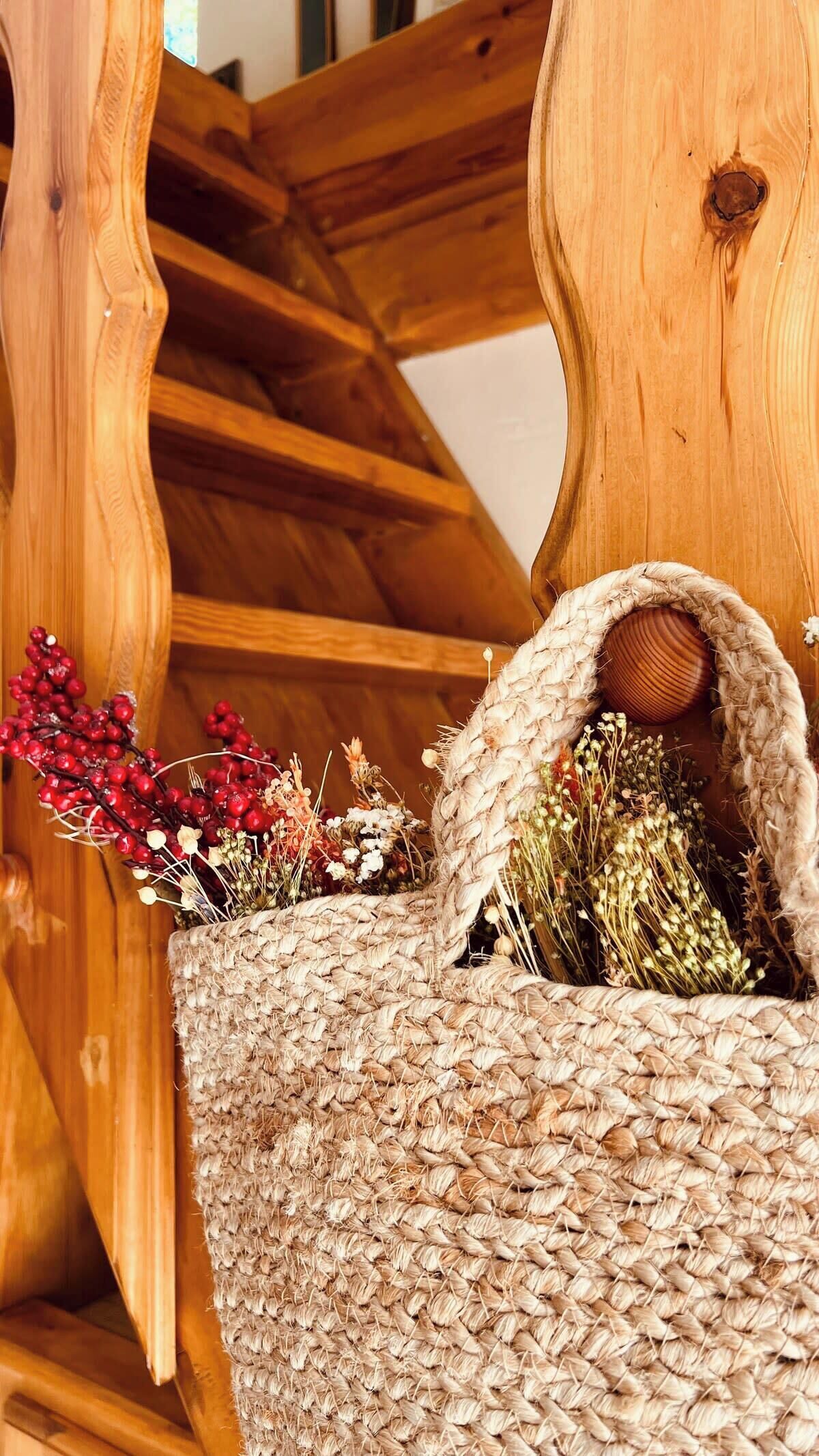A wooden chair with a woven basket containing dried flowers and berries.