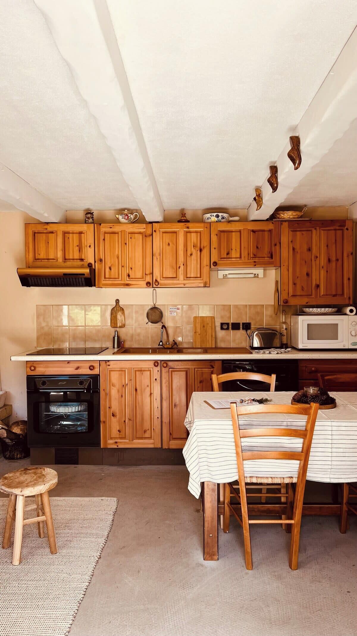 Una cocina con armarios de madera, estufa, horno, microondas y una mesa de comedor con sillas.