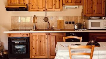 Una cocina con armarios de madera, estufa, horno, microondas y una mesa de comedor con sillas.