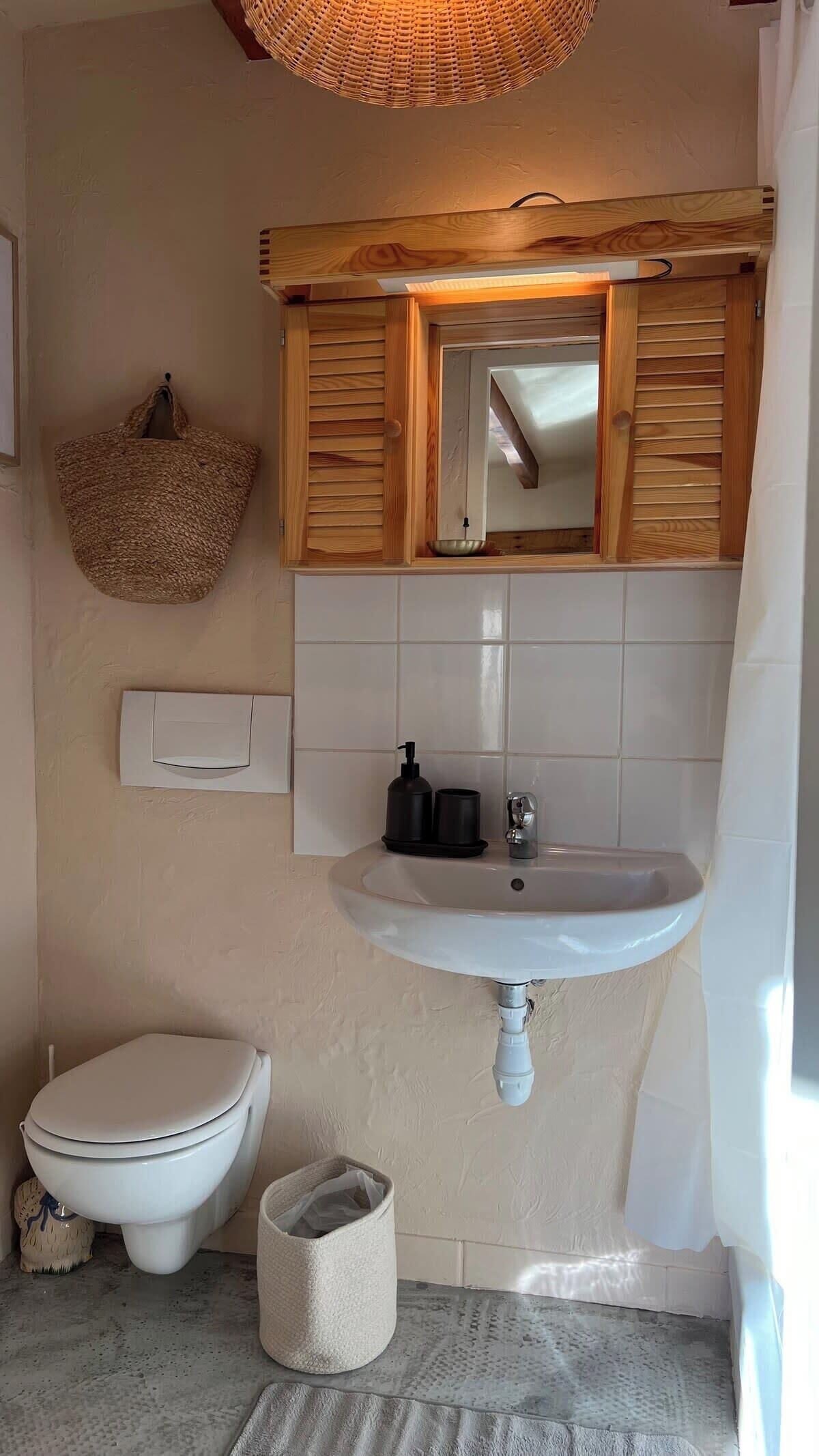 A bathroom with a wooden vanity, a white sink, and a toilet.