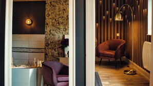 Ein modernes Badezimmer mit einer Steinwand, einem Waschbecken, einem violetten Sessel und einer Stehlampe.