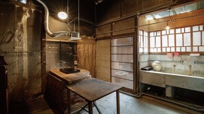 A rustic room with a wooden table, a window with bars, and a light fixture. - Mitoyotsuru Toji by Toma Rutto (Mitoyo)
