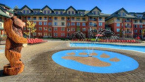 Un hôtel doté d’une grande piscine dont le motif présente des empreintes de pattes, ainsi que d’une sculpture en bois et d’une fontaine.