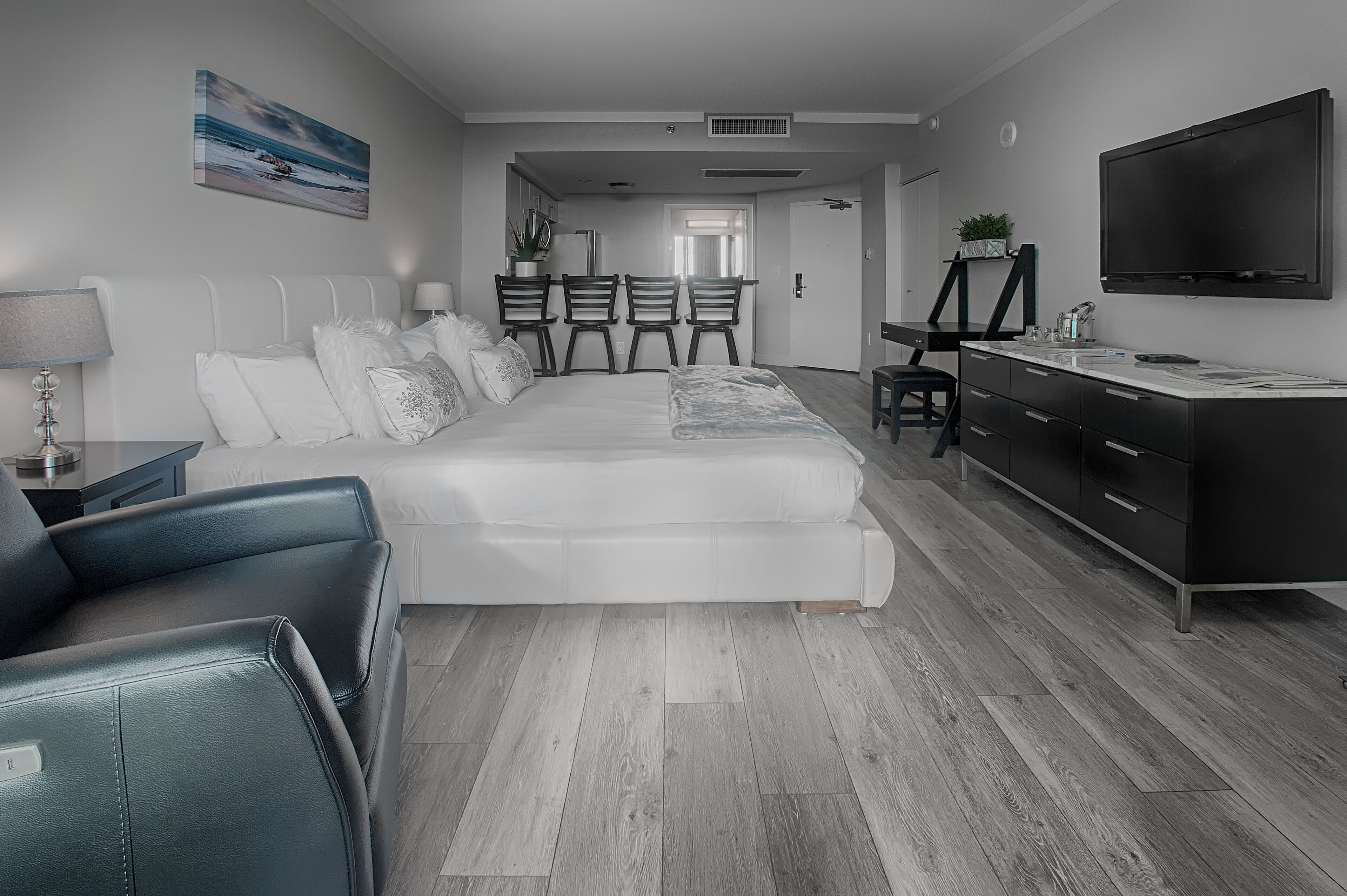 A modern bedroom with a large bed, a desk, and a TV.