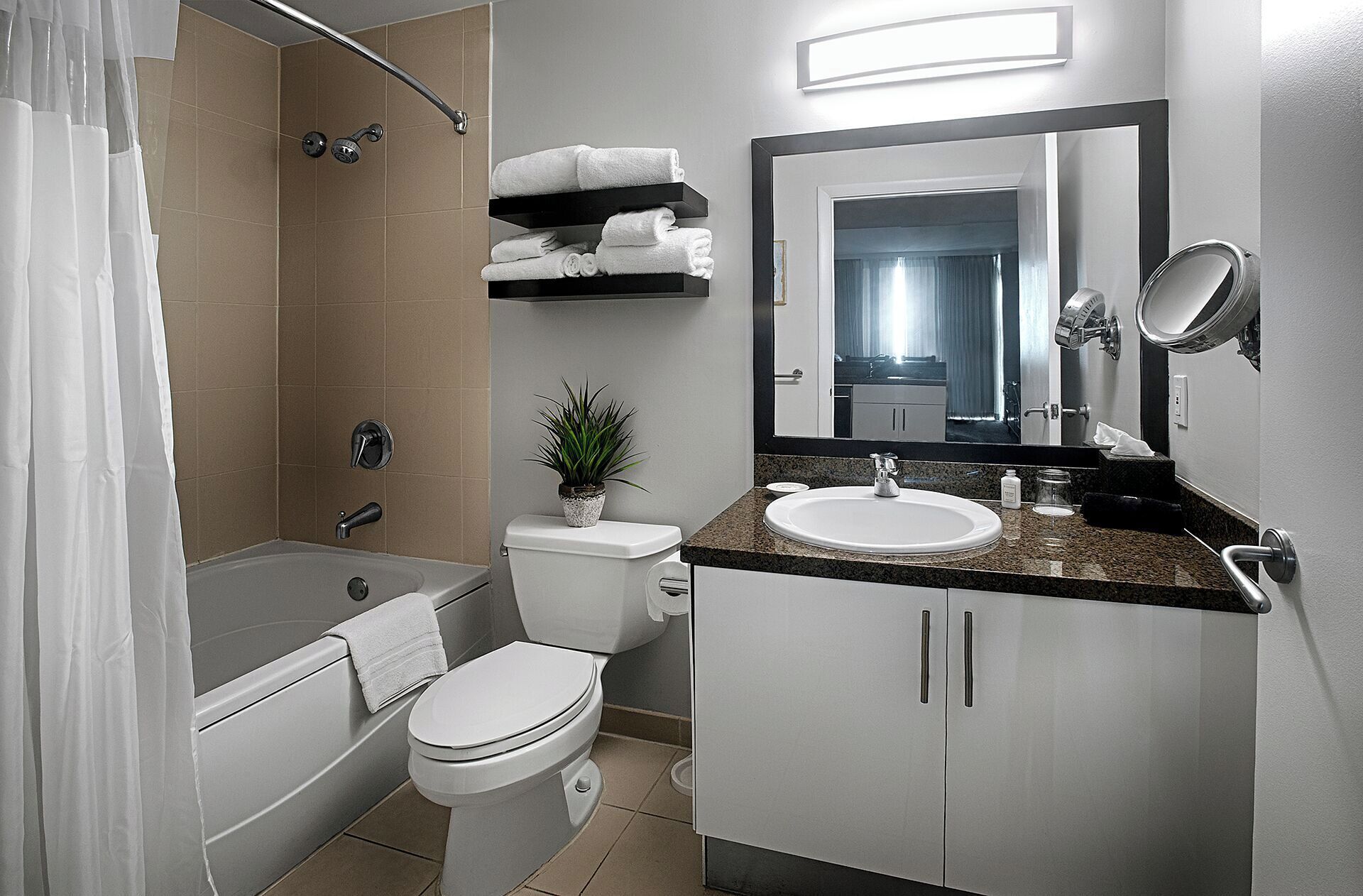 A modern bathroom with a bathtub, toilet, sink, and a large mirror.