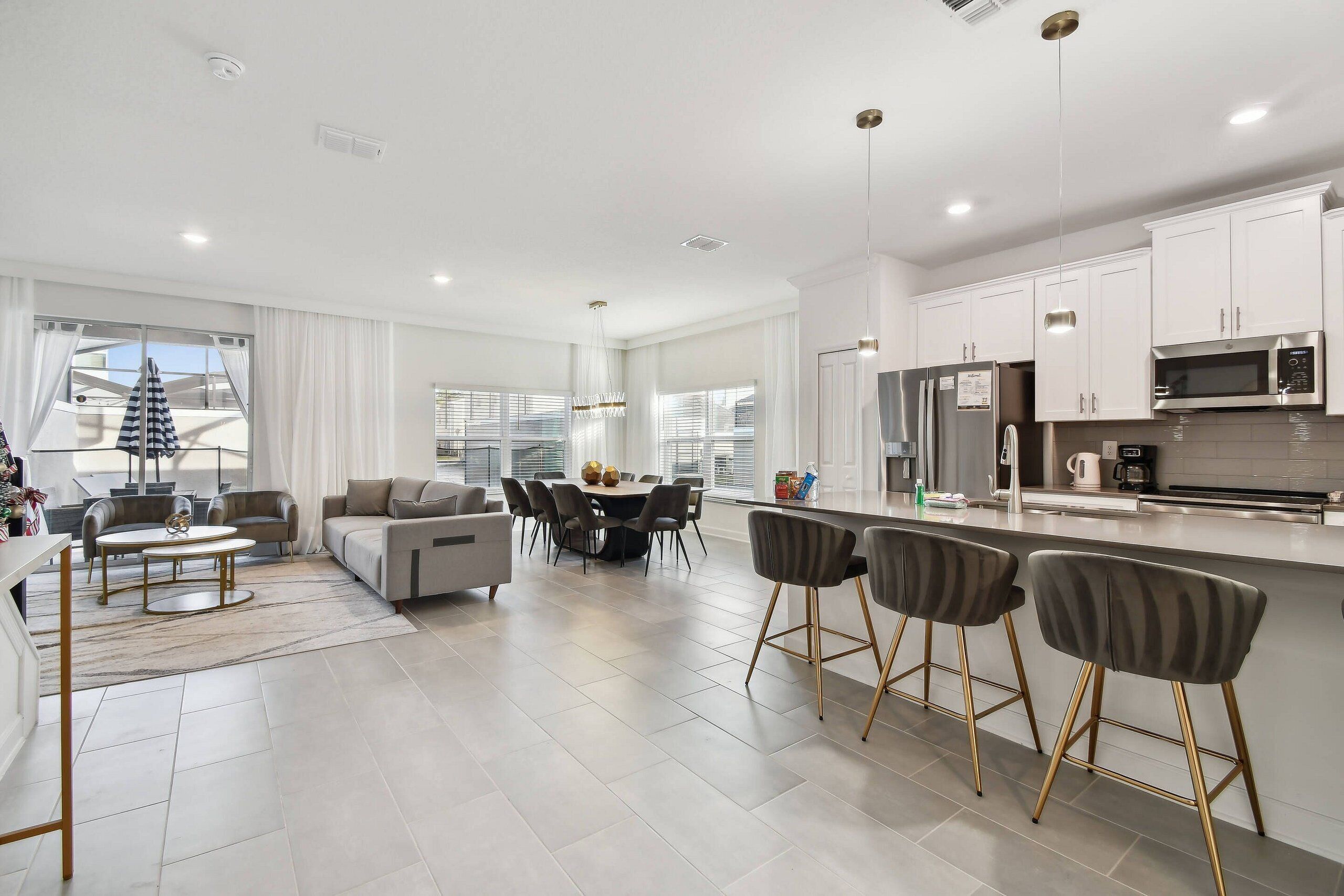 A modern kitchen with white cabinets, stainless steel appliances, and a bar area with stools.