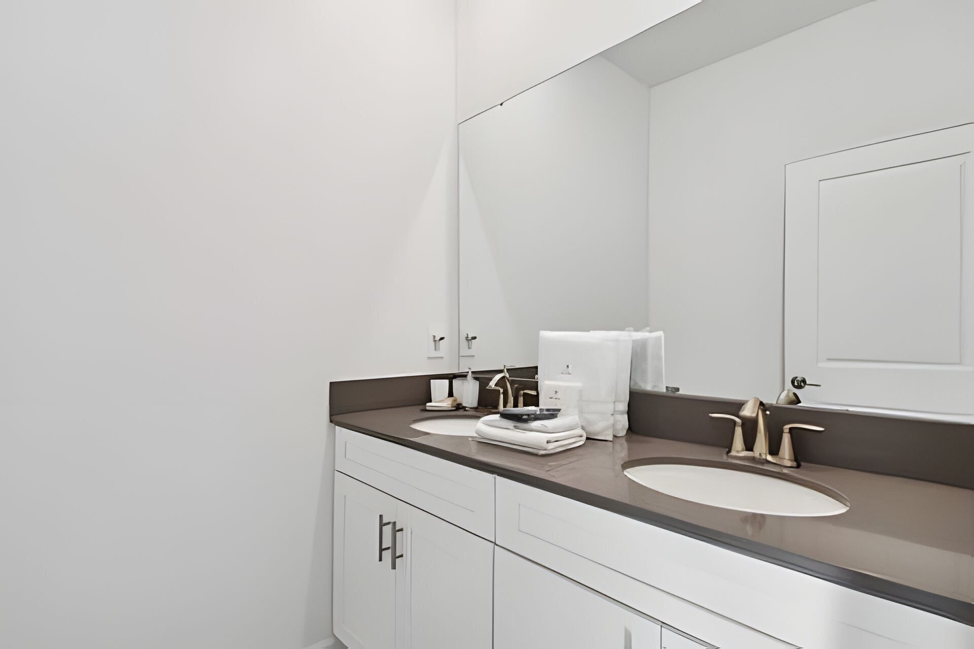 A modern bathroom with a large mirror, a sink, and a countertop.