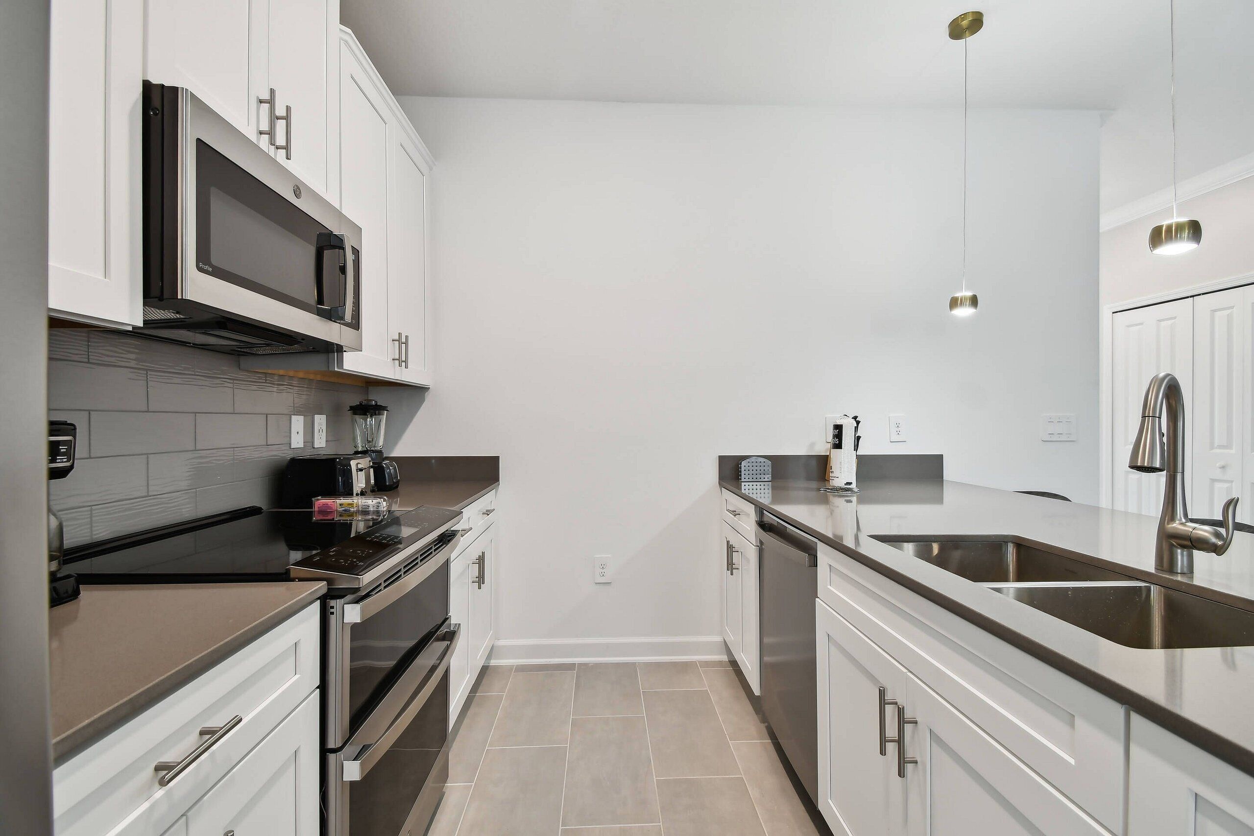 A modern kitchen with white cabinets, stainless steel appliances, and a double sink.