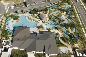 Oversigtsbillede af et resort med en stor swimmingpool, flere vandrutsjebaner og velplejede omgivelser.