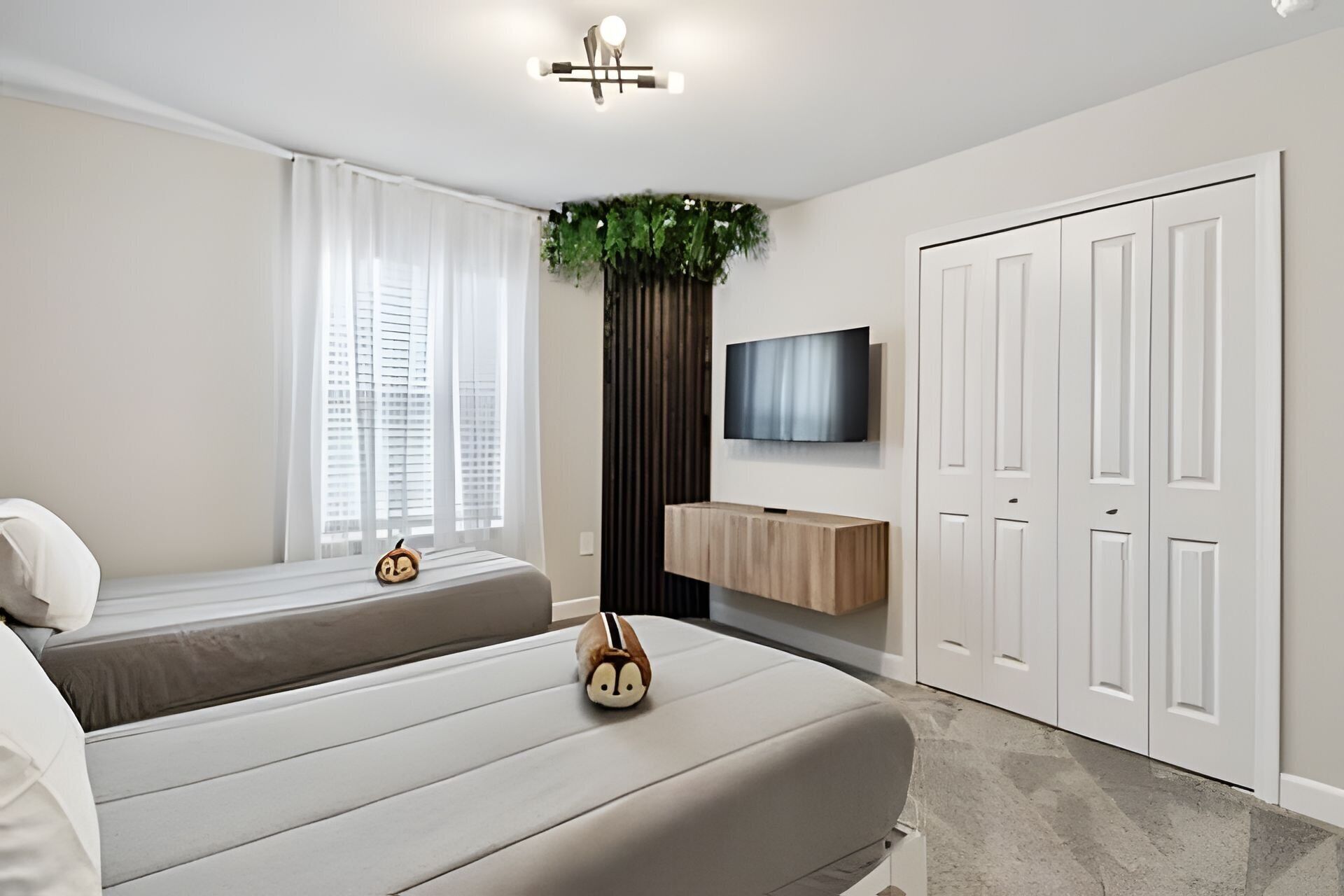 A modern bedroom with a bed, a TV mounted on the wall, and a wardrobe.