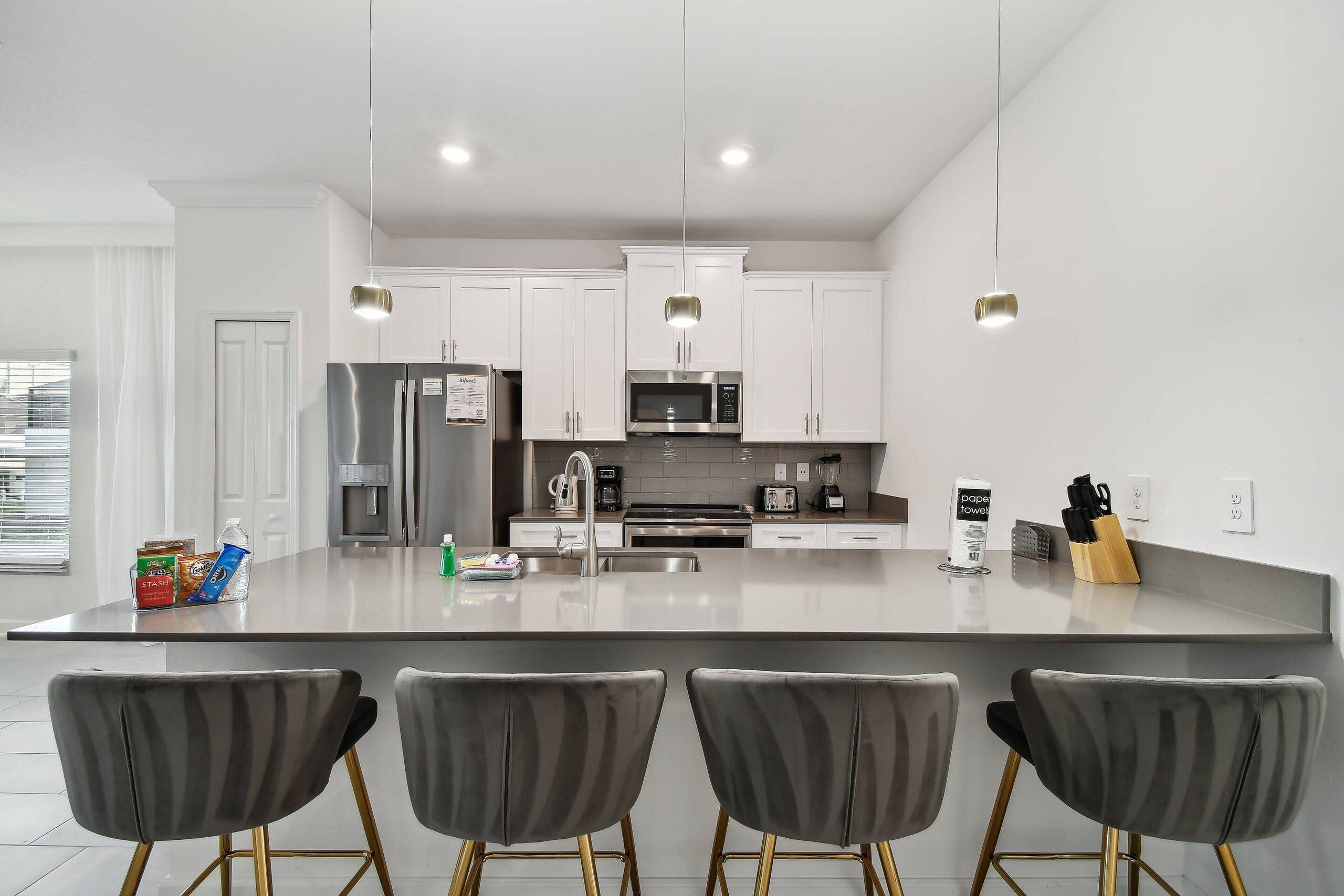 A modern kitchen with white cabinets, stainless steel appliances, and a central island with bar stools.